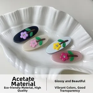 Detail of four acetate hair clips with floral rhinestone patterns in a shell tray