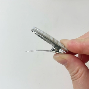 Detail view of oval acetate hair clip showing the metal alligator spring and marble pattern