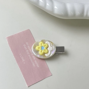 Close-up of colorful flower hair clip with iridescent oval base and silver metal duckbill
