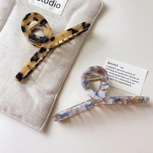 Elegant large acetate claw clips in tortoiseshell and marble blue patterns on beige background