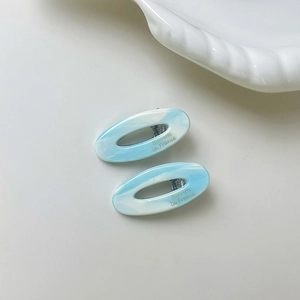 Detail of oval hollow hair clips featuring sky blue and white marble acetate texture