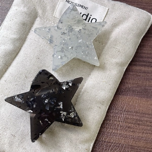 Star-shaped hair claw clips with silver glitter finish in translucent white and black