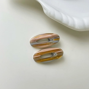 Macro view of oval tortoiseshell acetate hair clips with silver metal spring closure
