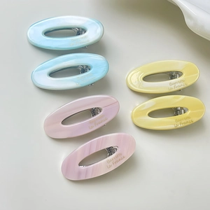 Detailed macro view of marbled acetate oval hair clips with golden French script