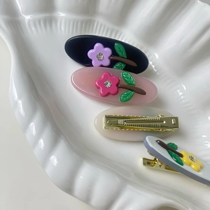 Set of four elegant acetate hair clips with rhinestone flower and green leaf details