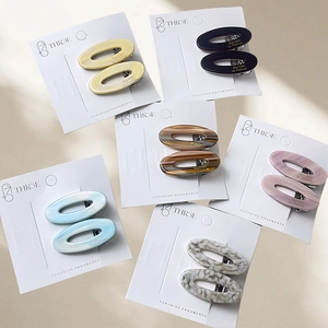 Oval acetate hair clips in six colors featuring gold labels on white display cards