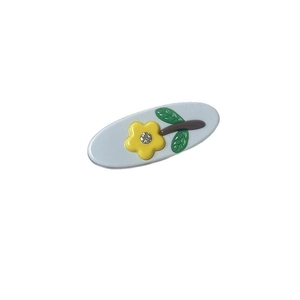 Elegant oval acetate hair clip with yellow rhinestone flowers and green leaves on white background