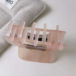 Dettaglio della pinza per capelli in acetato rosa traslucido con elegante trama marmorea