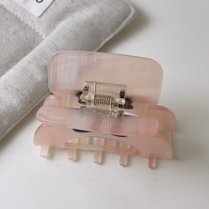 Dettaglio della pinza per capelli in acetato rosa chiaro con molla in metallo dorato