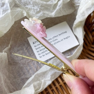Détail de la pince à cheveux fleurs roses avec cœurs en perles et base dorée en métal