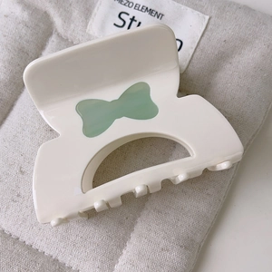 Dettaglio molletta per capelli crema in acetato con fiocco verde trasparente