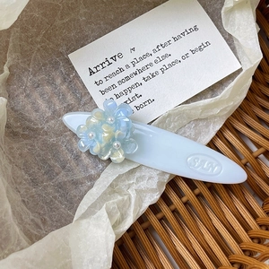Détail d'une pince à cheveux fleur bleue avec perle sur texture tressée