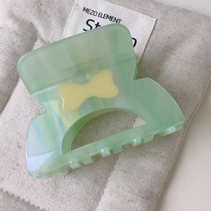 Dettaglio del fermaglio per capelli in acetato verde menta con trama marmorea e fiocco