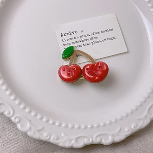 Macro detail of a cherry-shaped hair claw clip with red rhinestones on a white plate