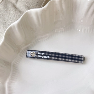 Macro view of blue plaid hair clip with heart rhinestone and lar mood text on ceramic
