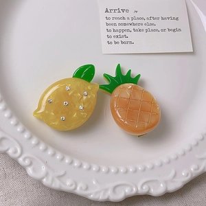 Detail showing acetate lemon and pineapple hair clips with rhinestones and carved texture
