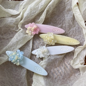 Lot de quatre barrettes à fleurs pastel avec perles sur un fond doux et épuré