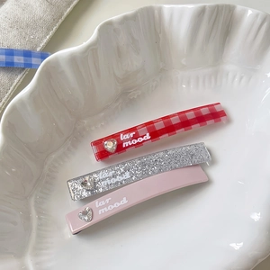 Close-up of three sweet hair clips with heart rhinestones and lattice patterns