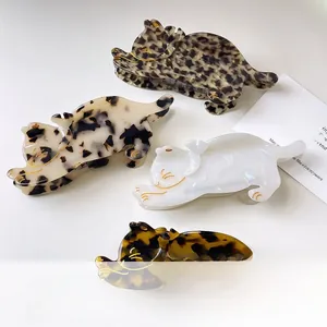 Detailed macro view of four acetate cat hair claw clips in tortoiseshell and marble patterns