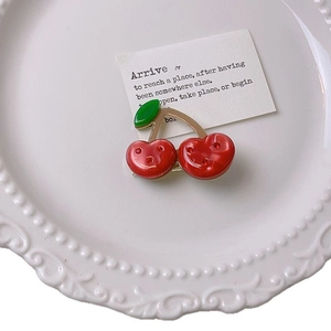 Cute cherry shaped hair clip with red crystals and green leaves on an elegant white plate