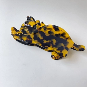 Detailed close-up of tortoise shell acetate cat hair claw with elegant gold outlines