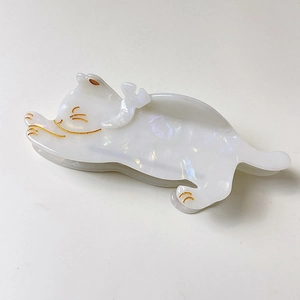 Detail of pearlescent white cat hair claw clip with golden eyes and paw print accents
