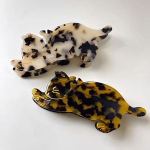 Detailed macro view of two acetate cat-shaped hair claws with elegant gold outlines