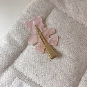 Close-up of pink marbled acetate bear hair clip with golden metal duckbill fastener