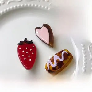 Vue détaillée des barrettes en acétate brillant aux formes de fraise et de cœur