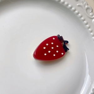Détail d'une mignonne pince à cheveux fraise sur une assiette en porcelaine blanche gaufrée