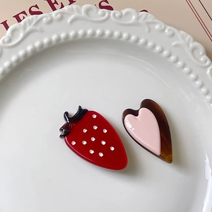 Lot de barrettes mignonnes en forme de fraise et de cœur sur une assiette en porcelaine
