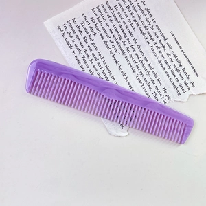 Macro detail of purple marble acetate comb with anti-static teeth on paper background