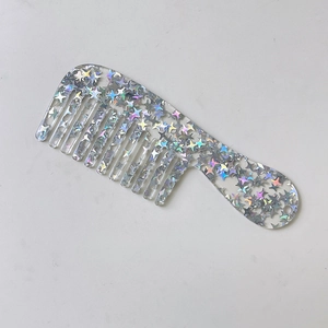 Macro view of a portable wide-tooth hair comb with glittery stars in transparent resin