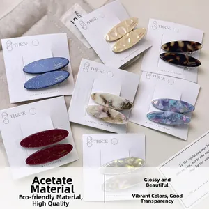 Close-up of various oval acetate hair clips in multiple colors with glitter and textures
