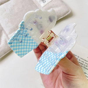 Close-up of blue checkerboard hair claw clip held in hand with premium acetate texture