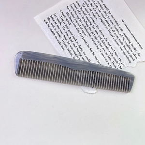 Detail view of anti-static acetate hair comb with grey marble pattern on vintage book