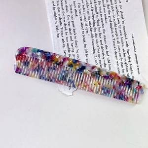 Detail of colorful acetate marble hair comb with wide teeth on a vintage book