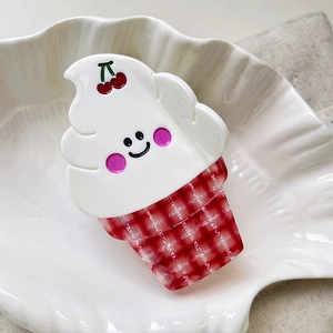 Close-up of ice cream hair claw clip with cherry and red checkered pattern on a shell plate