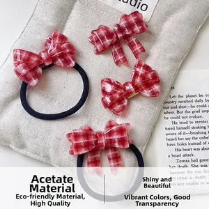 Dettaglio del fermaglio e dell'elastico in acetato a quadretti rossi e bianchi su rivista