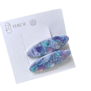 Set of two oval acetate hair clips with blue marble pattern and gold foil accents