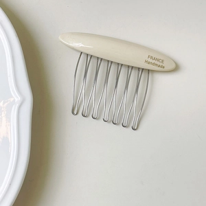 Macro detail of creamy acetate hair comb with golden France Handmade label and metal teeth