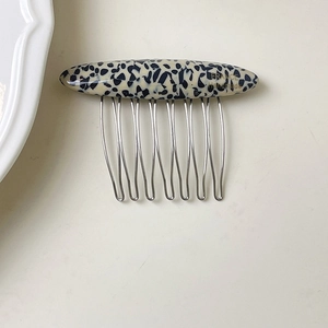 Detail of acetate French hair comb with ivory tortoiseshell pattern and 8 metal teeth