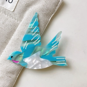 Détail d'une pince à cheveux en forme d'oiseau avec texture marbre vert sur un sac