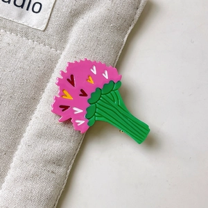 Détail d'une broche fleur d'oeillet rose avec des cœurs colorés et une tige en métal