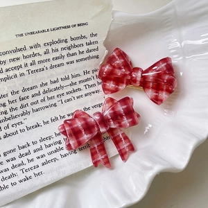 Dettaglio di fermagli per capelli a quadretti rossi con fiocchi su libro vintage
