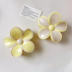 Detailed macro view of two-tone floral hair claws with polished glossy finish