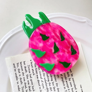Dettaglio di una molletta per capelli a forma di pitaya con finitura rosa e verde