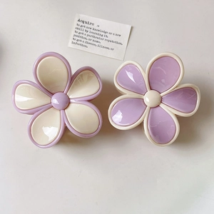 Close-up of large floral hair claws in purple and cream resin with a glossy finish