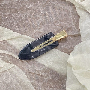 Close-up of marble pattern acetate hair clip with golden metal duckbill clip design