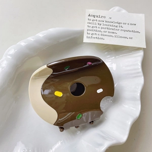 Gros plan détaillé d'une pince à cheveux beignet au chocolat sur une assiette coquillage